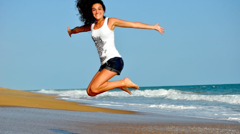 Una ragazza in salute salta sulla spiaggia e fa sport