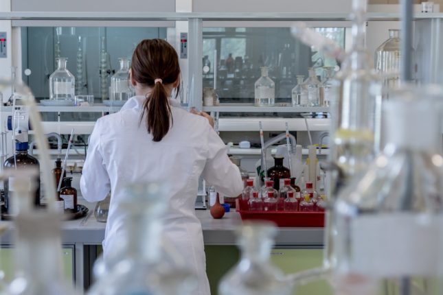 Una giovane ricercatrice, girata di spalle, lavora in laboratorio.